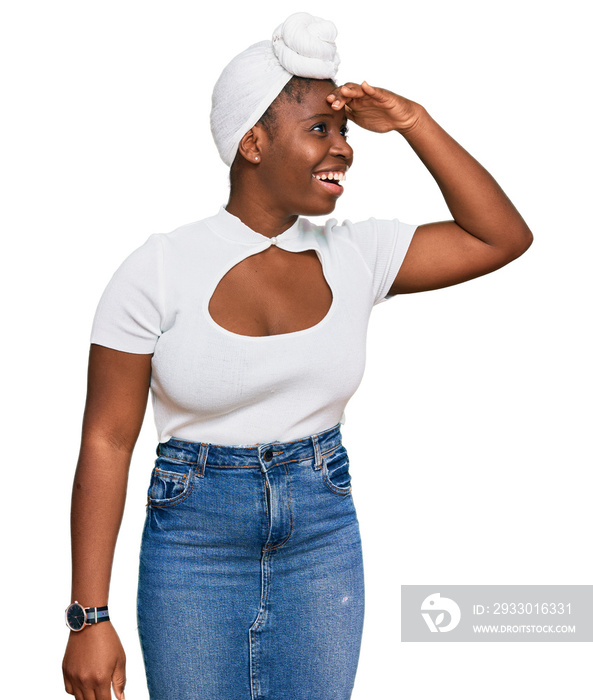 Young african woman with turban wearing hair turban over isolated background very happy and smiling looking far away with hand over head. searching concept.