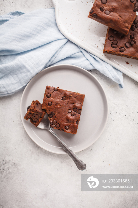 Piece of chocolate vegan cake with chocolate drops and nuts, top view.