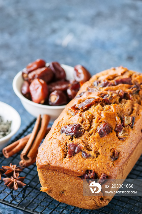 Honey and date spicy cake serving on a wire rack. Blue stone background.