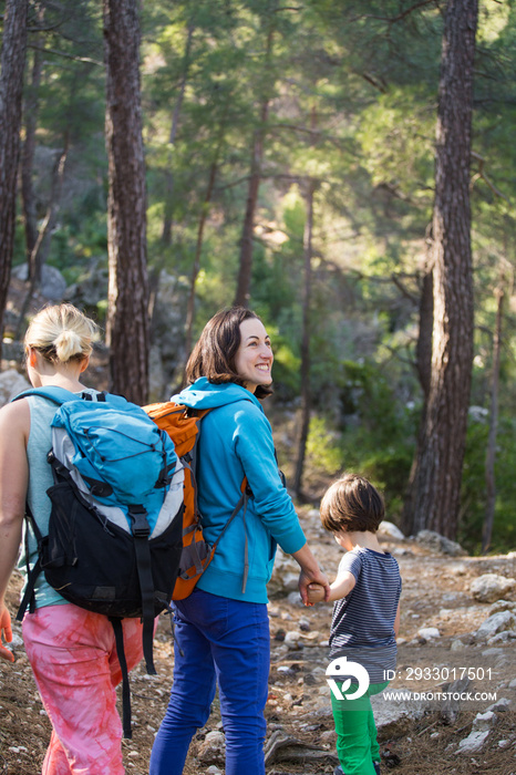 Two women and a child walk in the forest.