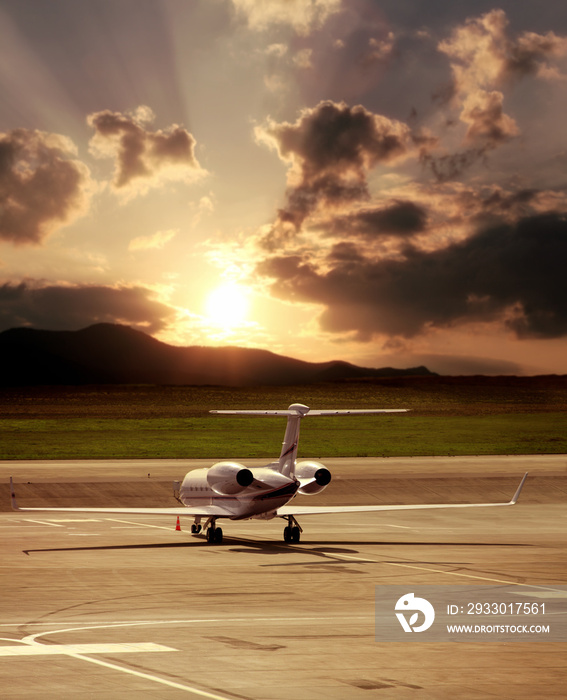 Close up private jet airplane parked at airport over cloudy sunset sky