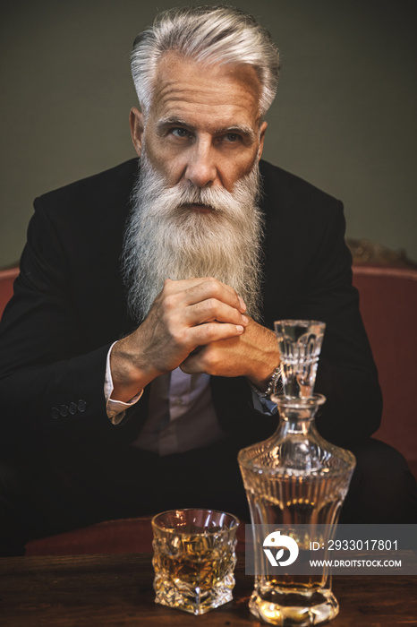 Handsome bearded senior man drinking whiskey