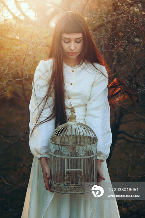 Beautiful young woman with bird cage