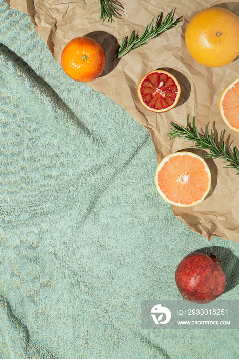 Summer scene with fruits,rosemary, glass of water and books on pastel green beach towel. Drinks and refreshment concept. Sunlit flat lay. Minimal style. Top view.