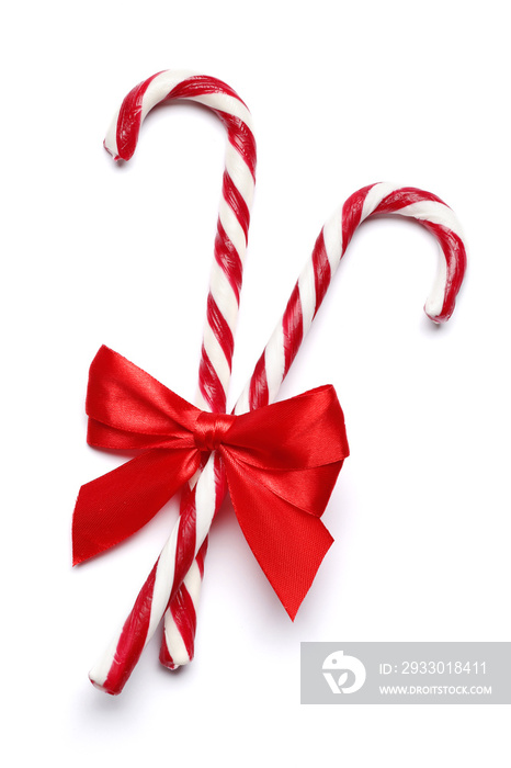 Tasty red candy cane with bow on white background. Festive treat