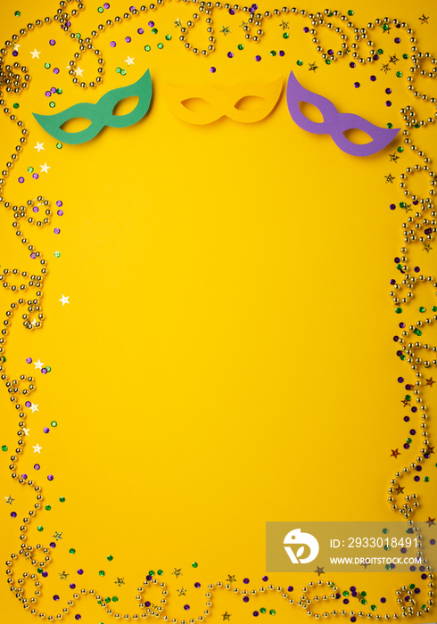 Mardi Gras gold color beads with Masquerade festival carnival masks and golden, green, purple confetti on yellow background.