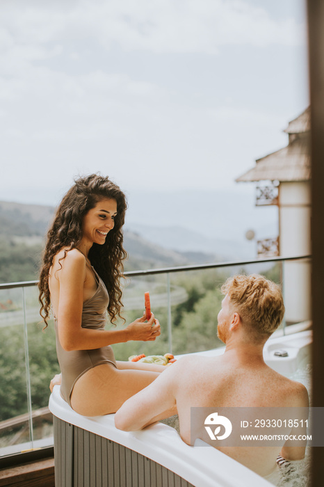 Young couple enjoying in outdoor hot tub on vacation