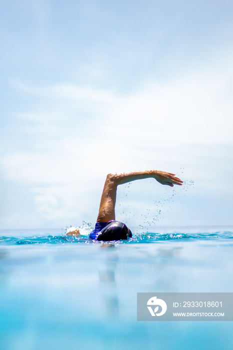 Unidentified woman doing front crawl swimming in swimming pool on vacation.