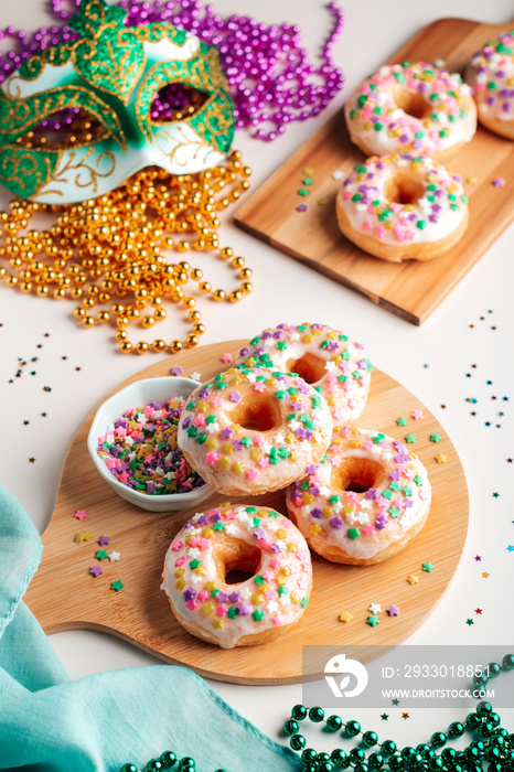 Mardi gras carnival sprinkled doughnuts and beads, holiday celebration, baking, top view