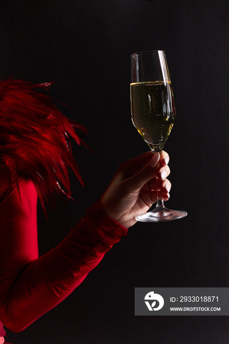 A girl in a beautiful red dress holds a glass of champagne in her hands