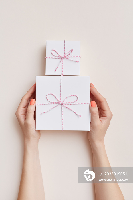 Mock up of white present boxes in women’s hands on the biege background