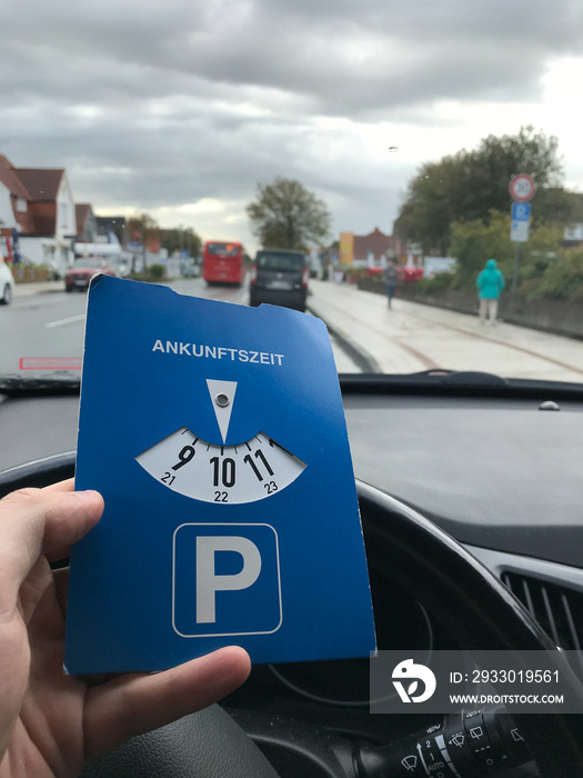 Blue parking disc in the hand of a driver sitting in the car