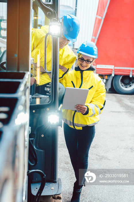 Worker and manager at distribution center behind a forklift