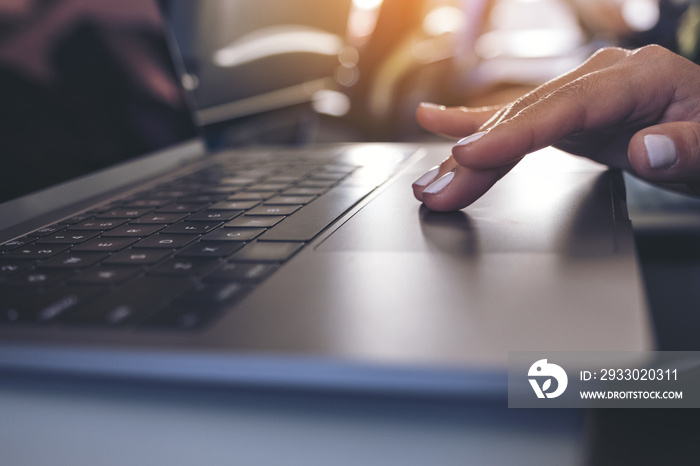 Closeup image of a woman using and touching at laptop computer touchpad while sitting in the cabin