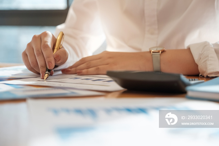 Close up Business woman using calculator and laptop for do math finance on wooden desk in office and business working background, tax, accounting, statistics and analytic research concept