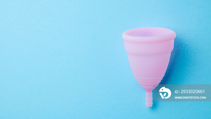 Silicone menstrual cup. Women’s health and alternative hygiene. Blue background.