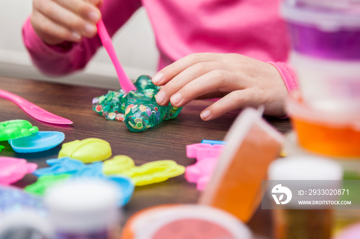 Young kids playing with colorful slime kit with glitter, toys, texture craft balls, and sparkles