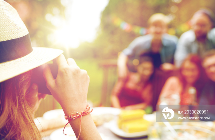 woman photographing friends at summer garden party