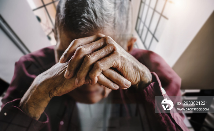 senior man covering his face with his hands.