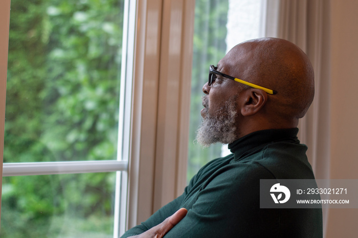 Mature man looking out living room window