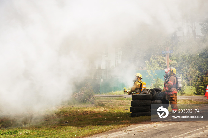 Firefighters standing by stack of tires