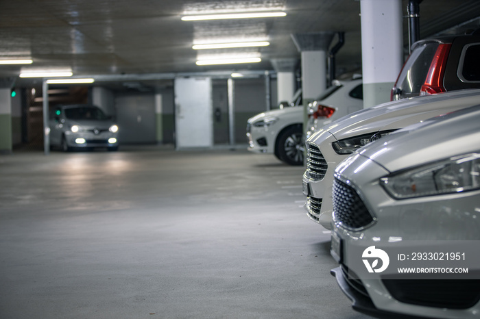 Underground parking. Cars parked in a garage with no people. Many cars in parking garage interior. Underground parking with cars (color toned image)