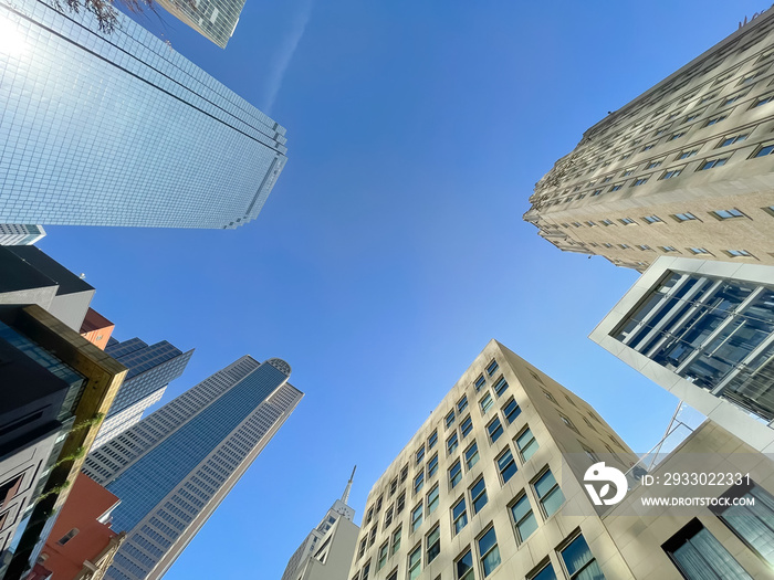 Lookup view skyscrapers and corporate office buildings under clear blue sky along Main Street in Downtown Dallas, Texas, America