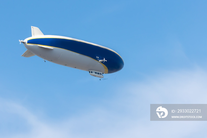 a white and blue blimp flying through the clouds