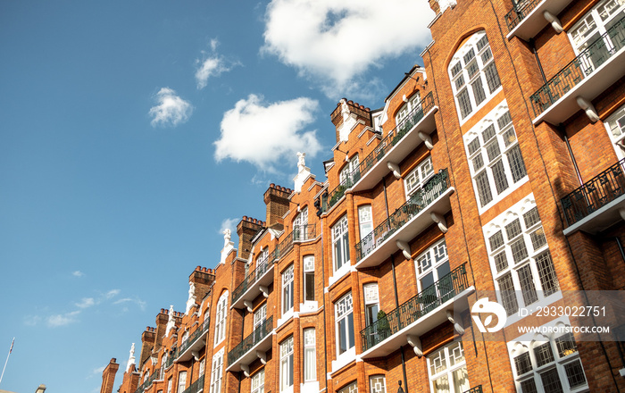 Looking up at red brick London townhouses against blue sky