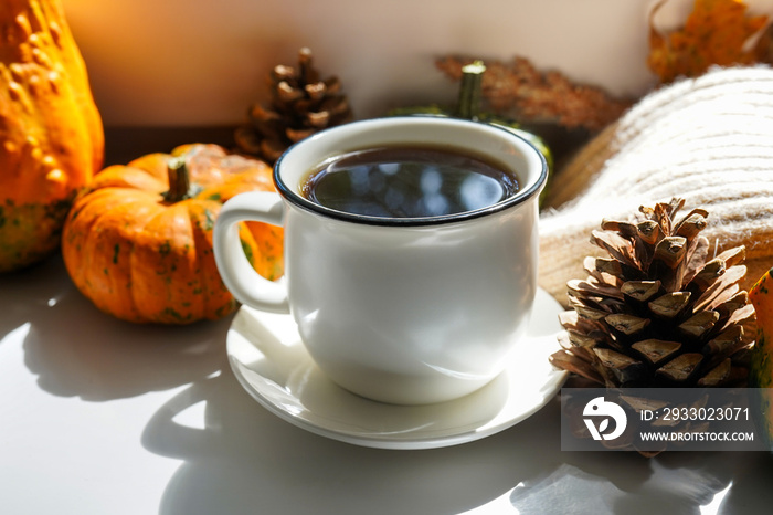 Autumn hot steaming cup of coffee and a warm scarf on white table background. Seasonal, morning coffee, Sunday relaxing and still life concept