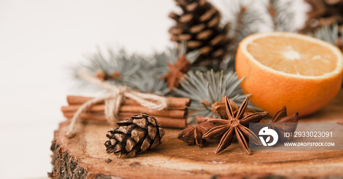 Christmas spices, cones and orange on wooden background.