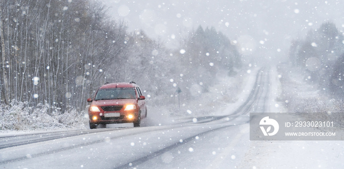 The car is driving on a winter road in a blizzard