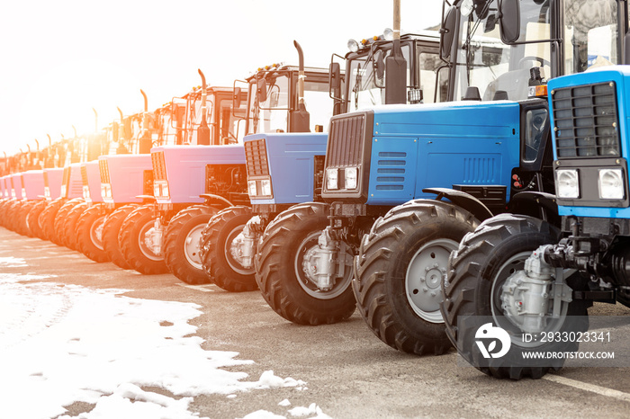 Many different tractors standing in row at agricultural fair for sale outdoors.Equipment for agriculture.Heavy industrial machines presented to an agricultural exhibition