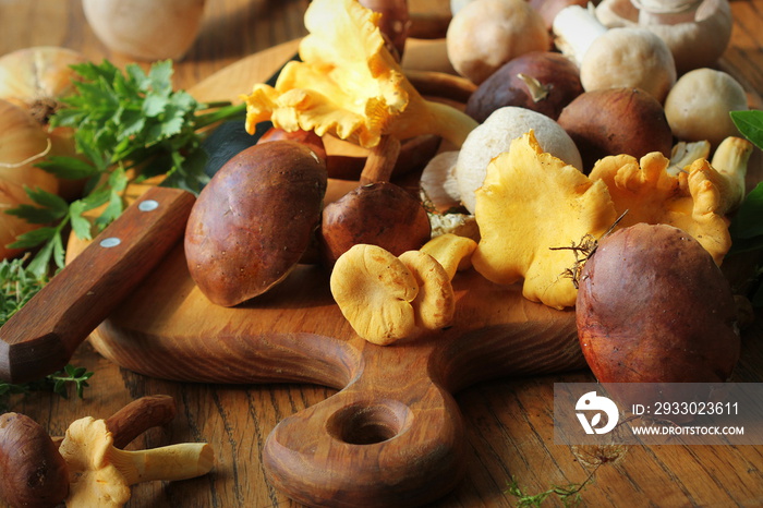 Mix of forest mushrooms on cutting board over old wooden table