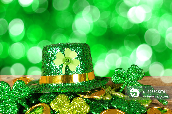 St Patricks Day leprechaun hat on a pile of gold coins and shamrocks in front of a twinkling green background