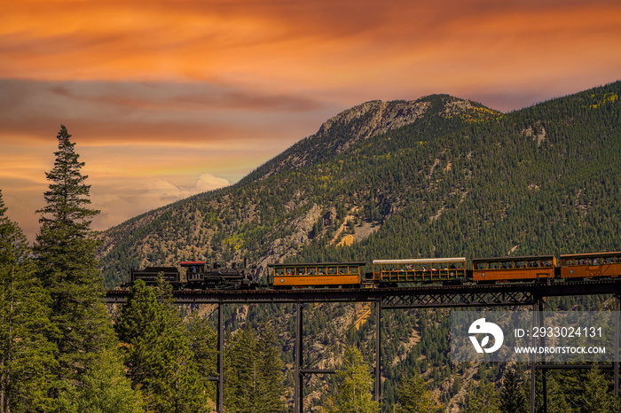 A vintage steam locomotive with tourist passenger cars on a high bridge on the Georgetown Loop Railroad in Georgetown Colorado