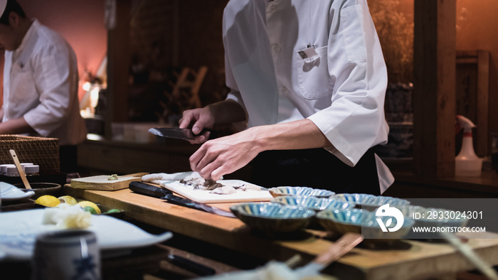 Chef preparing slicing oysters, Omakase style Japanese traditional.