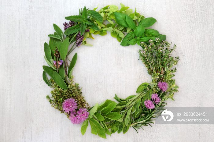 Herb leaf and flower wreath with a selection of fresh herbs with flowers on rustic wood background with copy space.