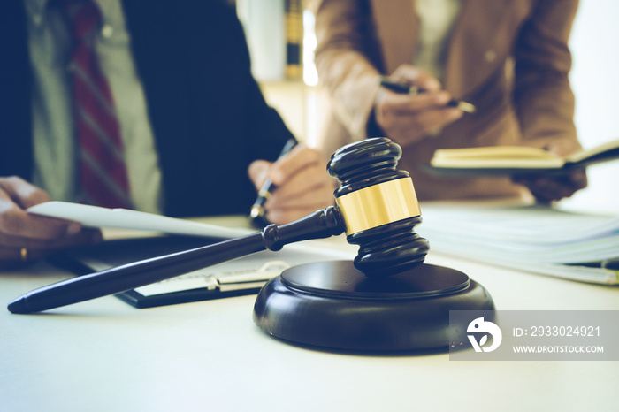 The lawyer and assistant are helping to review and will sign the document on the table had gavel and balance