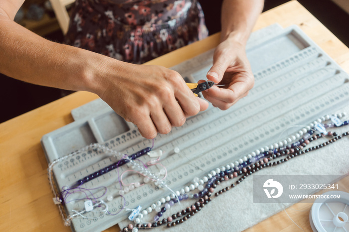 Close-up of woman making a necklace from gemstones