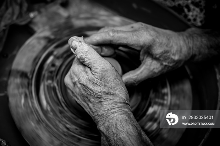 Hands of the potter. The potter makes pottery dishes on potter’s wheel. The sculptor in workshop makes clay product closeup