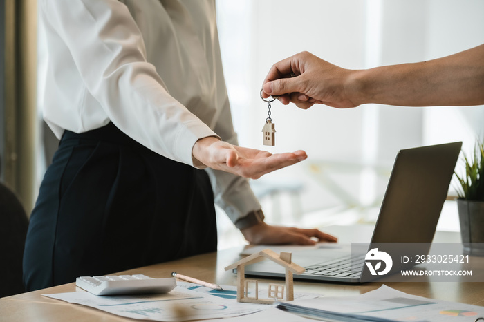 close up view hand of property realtor landlord giving a key house to buyer tenant at modern office