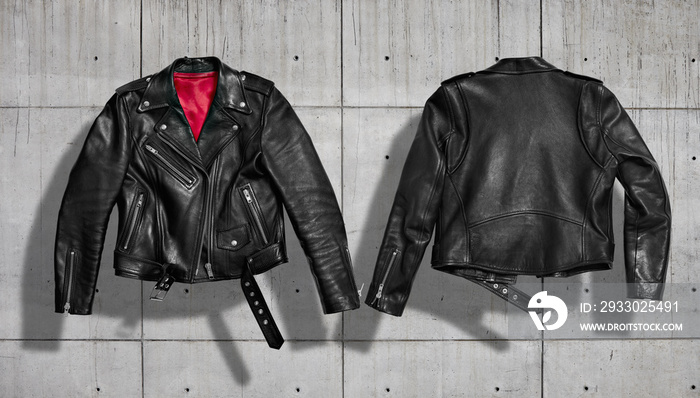 Classic women black leather bikers’ jacket with silk red lining shot from the front and the back isolated on neutral indastrial concrete gray background