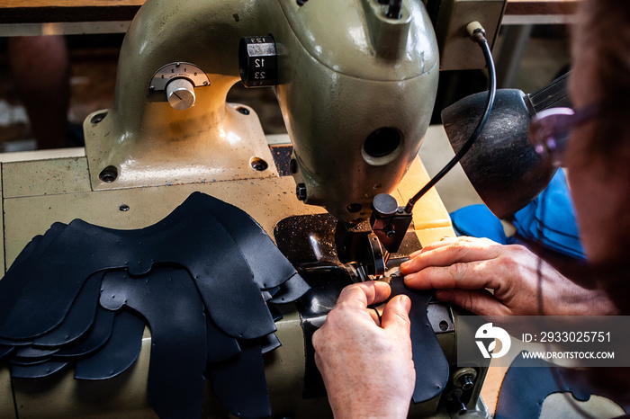 The master sews leather garments at the factory