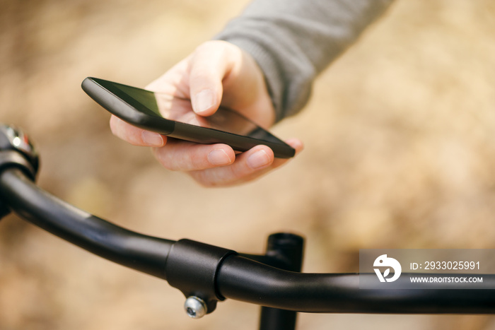 Woman using smart app on phone while riding bicycle