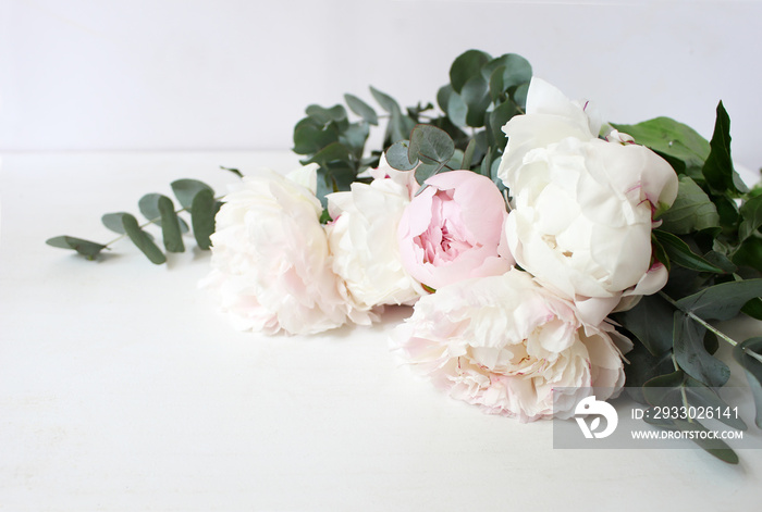 Styled stock photo. Decorative still life floral composition. Wedding or birthday bouquet of pink and white peony flowers and eucalyptus branches. White table background.