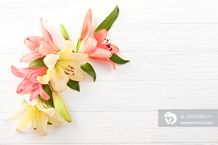 Beautiful lilies on light wooden background