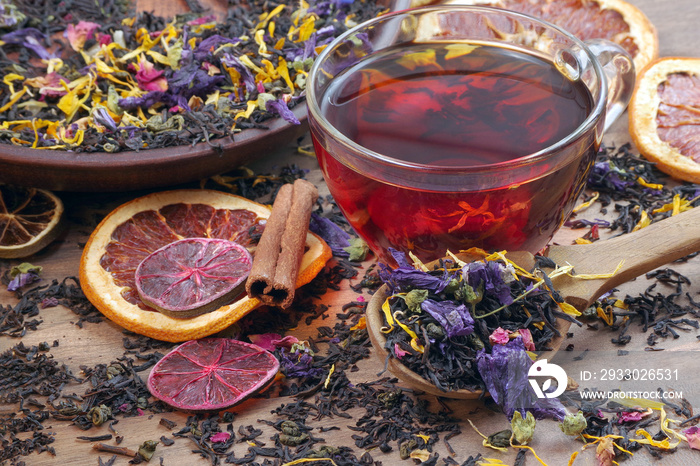 blended tea. black tea with dry flower petals and citrus fruits. dry black tea leaves in a wooden spoon and cup of fresh tea. close up