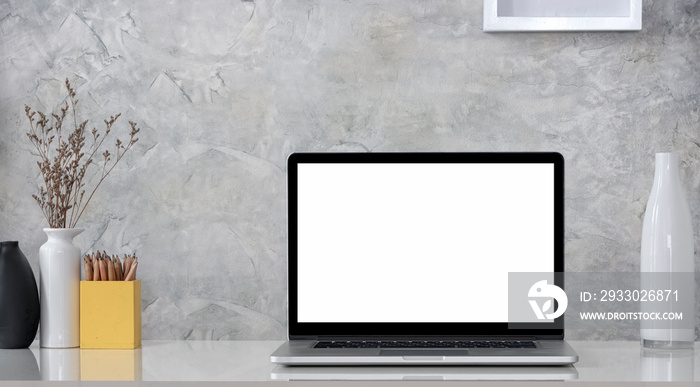 Creative workspace with blank screen laptop computer and decoration object on wooden table with concrete wall.