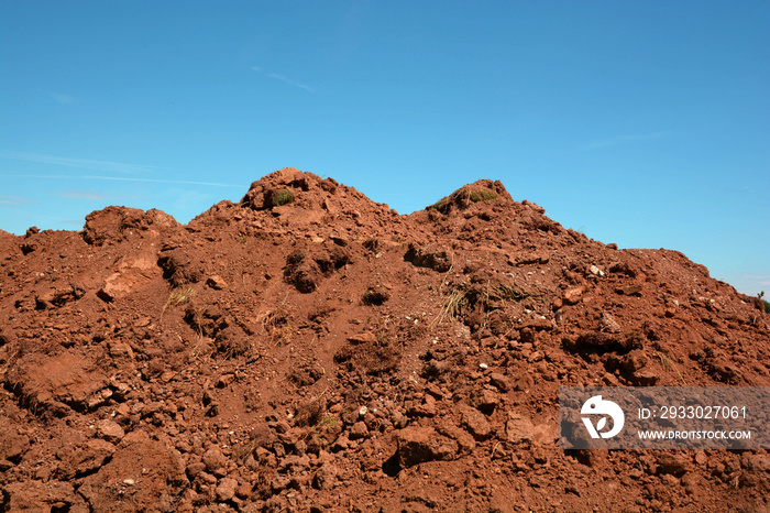 pile soil or dirt isolated on blue sky background in summer, dry soil pile and azure sky